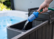 Gros plan d'un tuyau d'arrosage équipé d'un préfiltre bleu transparent inséré dans le compartiment de filtration d'un spa extérieur pour le remplissage d'eau pure.