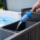 Gros plan d'un tuyau d'arrosage équipé d'un préfiltre bleu transparent inséré dans le compartiment de filtration d'un spa extérieur pour le remplissage d'eau pure.